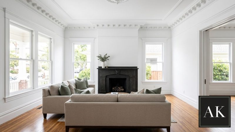 A bright living room in a historic home in Mission Hills with white walls, ornate crown molding, and a black fireplace.